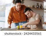 Small photo of Young man with Down syndrome preparing breakfast with his mother at home. Morning routine for man with Down syndrome.