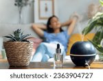 Shot of beautiful woman relaxing on a coach while essential oil aroma diffuser humidifier the air in living room at home
