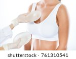 Portrait of female doctor choosing mammary prosthesis with her patient over white background.