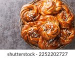 Kanelbullar or Kanelbulle is a traditional Swedish cinnamon buns flavored with cinnamon and cardamom spices and topped with pearl sugar close-up on a plate on the table. Horizontal top view