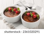 Small photo of Chocolate creme brulee dessert consisting of a rich custard base topped with a layer of hardened caramelized sugar close-up in a ramekin on the table. Horizontal