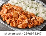 Small photo of Creamy casserole Flygande Jakob made of chicken, cream, chilli sauce, bananas, roasted peanuts and bacon served with rice closeup on the plate on the table. Horizontal