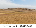 View of the highest sand dunes in the distance in the desert of the Paracas reserve in hot weather with haze in the air and cloudy skies