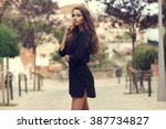 Young beautiful stylish girl in black summer dress walking and posing between trees at alley                               