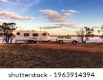 Landscape view of a a large white caravan and modern 4WD vehicle at a free camp next to the nearly dry salt Lake Norring near Wagin in Western Australia in late afternoon sunshine.