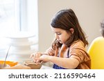 Cute little kid playing with modeling clay in pottery workshop, craft and clay art, child creative activities, education in Arts