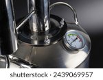 Small photo of brand new stainless steel alcohol machine or moonshine still on black background.