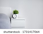 good morning concept - alarm clock and houseplant on bedside table and copy space over white wall background