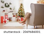 Woman relaxing on armchair in decorated room with christmas tree