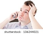 Small photo of Desperate young brown-haired businessman get bad news heavy problems, faces challenges snort and holding his head while talking on the mobile phone on white isolated background