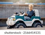 Happy little boy driving big toy car and having fun, outdoors.