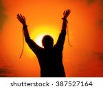 Silhouette of man agains the sunset ssky raising up his hands as he becomes free from chains and shackles