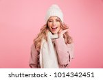 Image of happy young woman standing isolated over pink background wearing warm scarf. Looking camera.