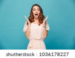 Image of shocked excited young lady standing isolated over blue background. Looking camera.