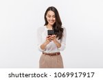 Portrait of a happy asian businesswoman using mobile phone isolated over white background