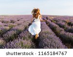 Back view of a pretty young girl in dress running at the lavender field