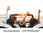 Image from back of beautiful multiethnic couple man and woman rejoicing while driving convertible stylish car by seaside