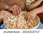 African woman eating popcorn with her children sitting on a couch at home