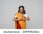 Young south asian woman wearing sari smiling while making namaste gesture isolated over white wall