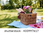 Closeup of picnic basket with drinks, food and flowers on the grass