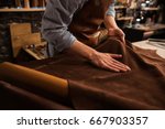 Close up of a male shoemaker working with leather textile at his workshop