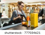 Smiling female cashier scanning grocery items at supermarket