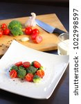 Small photo of Broccoli tomato salad with pepper, compositions with tuple and wooden board