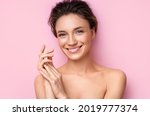 Beautiful woman applying moisturizer cream on her hands. Photo of smiling woman with perfect makeup on pink background. Beauty concept