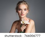Charming young girl with perfect makeup. Photo of blonde girl with rose on grey background. Skin care concept 