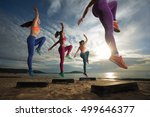 Small photo of fitness, training, aerobics and people concept - group of girls working out with steppers on the beach (Focus on front female body)