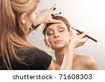 Backstage scene: Professional Make-up artist doing glamour model makeup at work