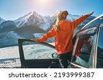 Woman traveling exploring, enjoying the view of the mountains, landscape, lifestyle concept winter vacation outdoors. Female standing near the car in sunny day, travel in the mountains, freedom