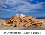 Small photo of Cigarette stubs dropped and left in a pile on a beautiful beach