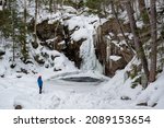 Small photo of Hikers near frozen Kinsman Falls in Franconia Notch State Park during winter . New Hampshire mountains. USA