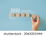 Small photo of Female hand putting wooden cube for countdown to 2022. Loading year from 2021 to 2022. New year start concept