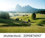 Scenic panoramic view of idyllic Dolomites mountain scenery with traditional wooden mountain huts at Alpe di Siusi in beautiful morning light at sunrise in spring, South Tyrol, northern Italy