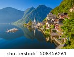 Scenic picture-postcard view of famous Hallstatt mountain village in the Austrian Alps with passenger ship in beautiful morning light at sunrise on a sunny day in summer, Salzkammergut region, Austria