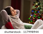 Young woman relaxing on chair in front of Christmas tree