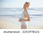 smiling elegant 40 years old woman in white swimwear at the beach relaxing.