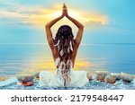 Small photo of Yoga Meditation at Sunset Beach. Peaceful Woman relaxing with Tibetan Singing Bowls. Indian Women Silhouette meditating over Sunshine Blue Sky background