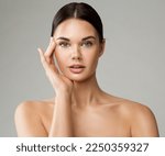 Beauty Woman Face with Perfect Smooth Skin. Young Model applying Eye Cream. Beautiful Girl with Full Lips Natural Makeup over White. Women Facial Plastic Surgery and Dermal Fillers