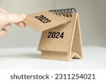 a woman's hand turns over a calendar sheet. year change from 2023 to 2024.