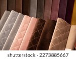 Fabrics in warm pastel colors in the catalog for choosing fabric for the production of new upholstered furniture, focus on brown textured fabric