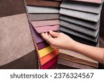 Small photo of A young girl is holding a fabric catalog for choosing fabric for upholstered furniture, the girl has chosen a pink fabric for her new sofa and wants to paint the walls pink