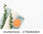 Rolled fluffy towels, orange bath salt and eucalyptus twigs on white background. Hygiene, wellness, body care concept. Copy space for text, top view