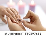 Nail Care And Manicure. Closeup Of Beautiful Female Hands Applying Transparent Nail Polish On Healthy Natural Woman's Nails In Beauty Salon. Manicurist Hand Painting Client's Nails. High Resolution