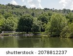 Small photo of Cookham Dean, UK - July 19, 2021: View across the River Thames looking towards the small boats of the Longridge Activity Centre at Cookham Dean in Berkshire on a sunny summer day.