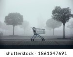 Abandoned shopping cart on parking lot in thick fog. Themes shopping, financial crisis and gloomy weather.