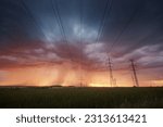 Landscape with electricity pylons under dramatic clouds of approaching rain with strong storm. Themes extreme weather, electrical energy and change climate.