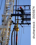 Small photo of Roustabout works on high platform of oil drilling rig, Kern County, California